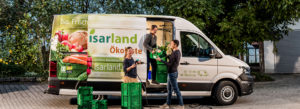 Beate Mayer, Nicole Göhring und Christian Suppenkämper (Isarland Ökokiste) laden Kisten in Lieferfahrzeug ein