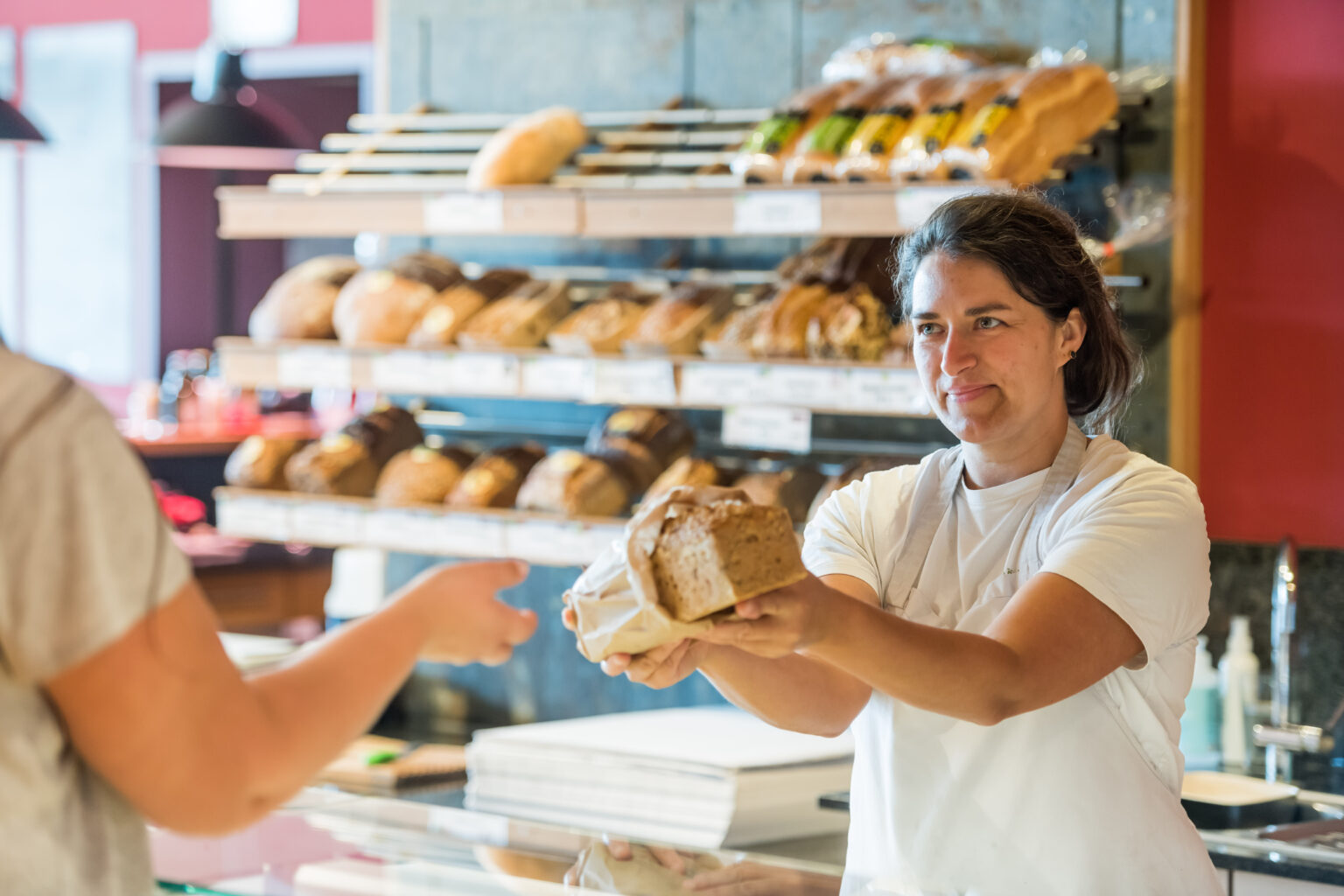 Verkäuferin übergibt Kunden Brot